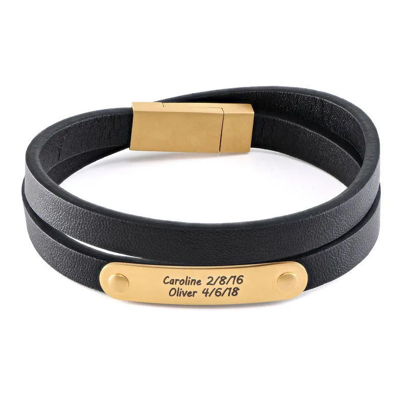 Stock image of a black leather bracelet with gold plated engraved bar 