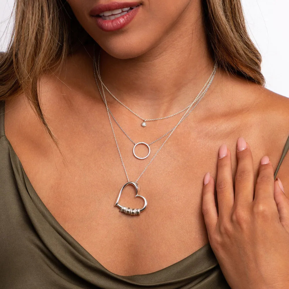 Woman wearing a silver necklace with a heart-shaped pendant with inscribed beads