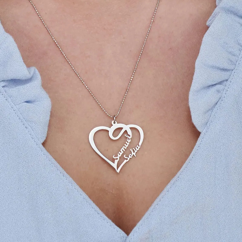 Woman wearing a white gold necklace with a heart shaped pendant  and engraved names