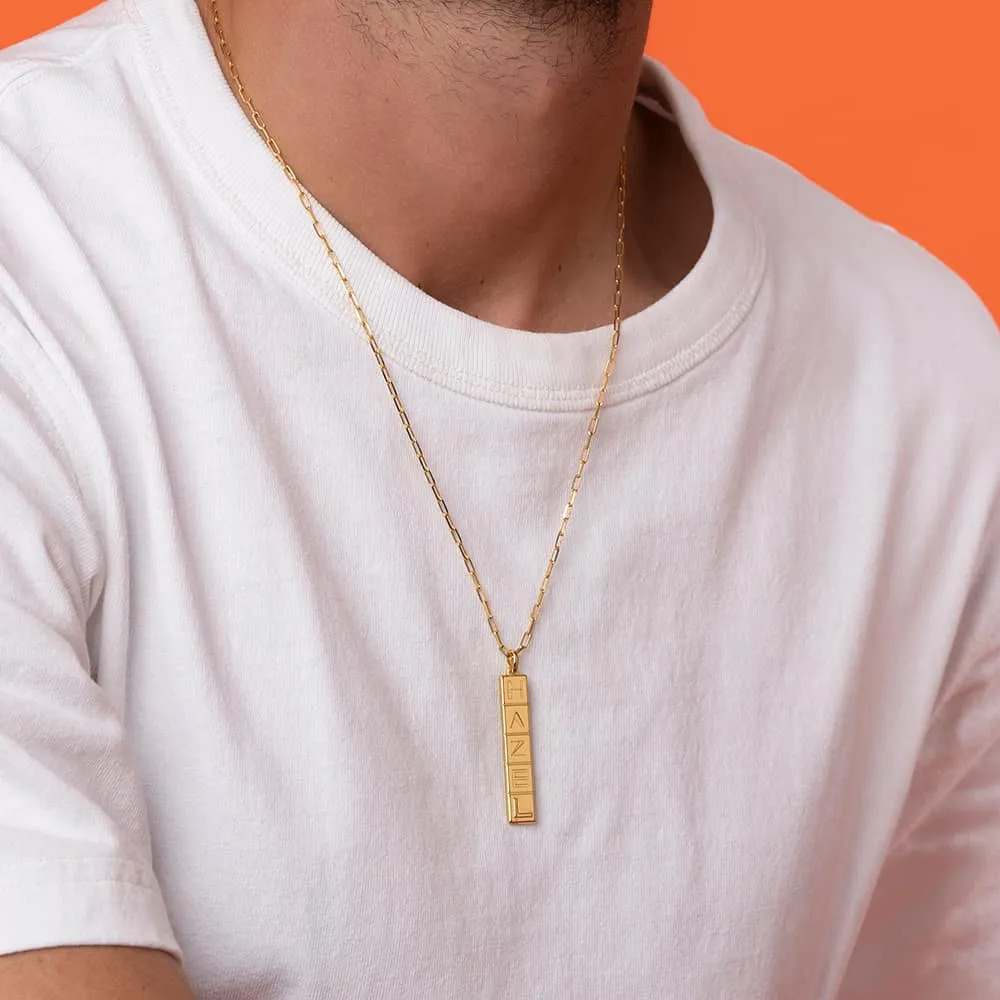 Man wearing a gold vermeil necklace with a vertical tile pendant around his neck 