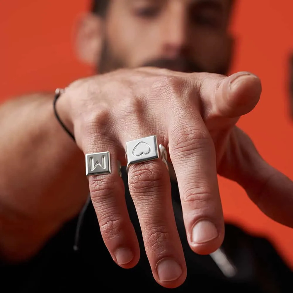 A man wearing Domino tile shaped initial rings on his pinky and ring finger 