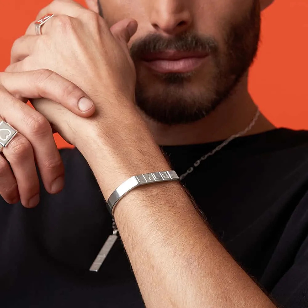 A man wearing a sterling silver wrist band with Domino tile initials
