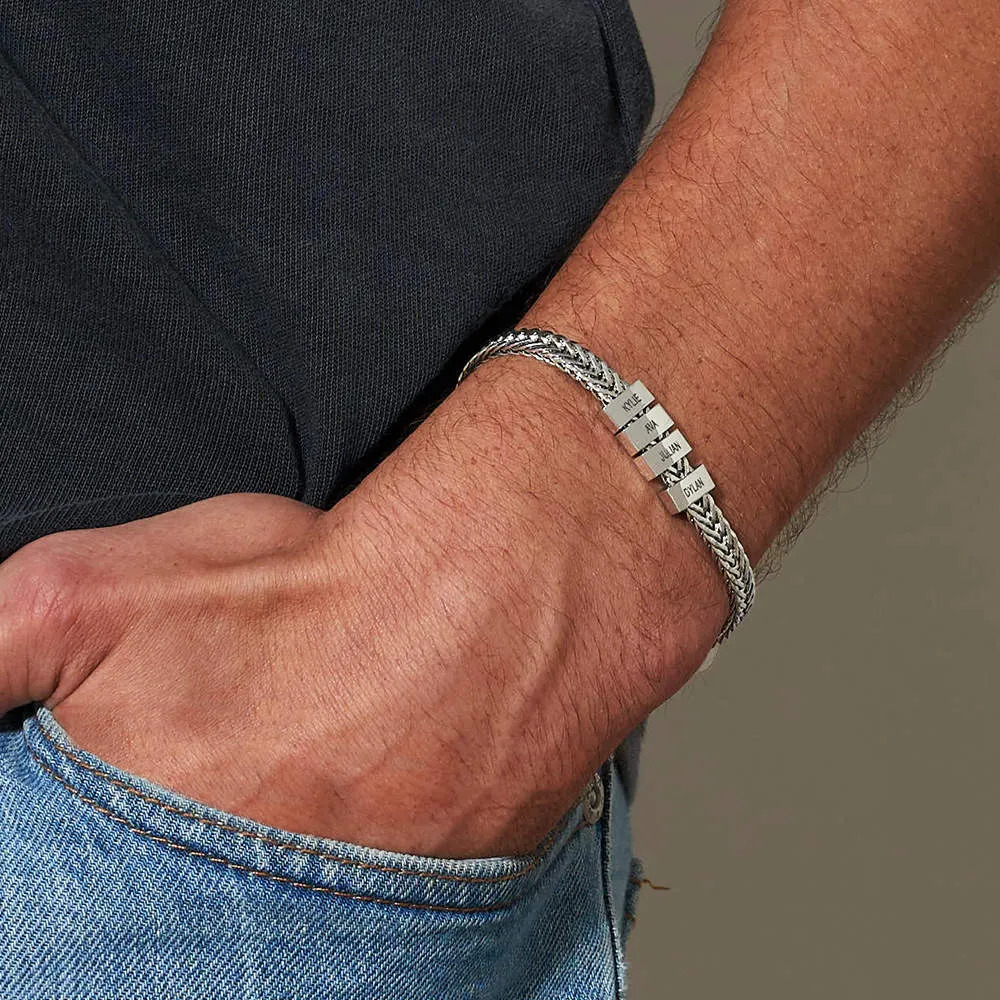Man wearing a stainless steel bracelet with inscribed charms on their wrist