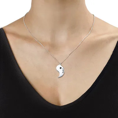 A woman wearing one half of a yin yang couples necklace  with engraving and a birthstone 