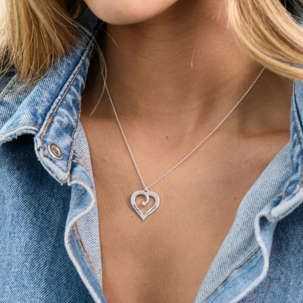 Woman wearing a silver necklace with a heart shaped pendant 
