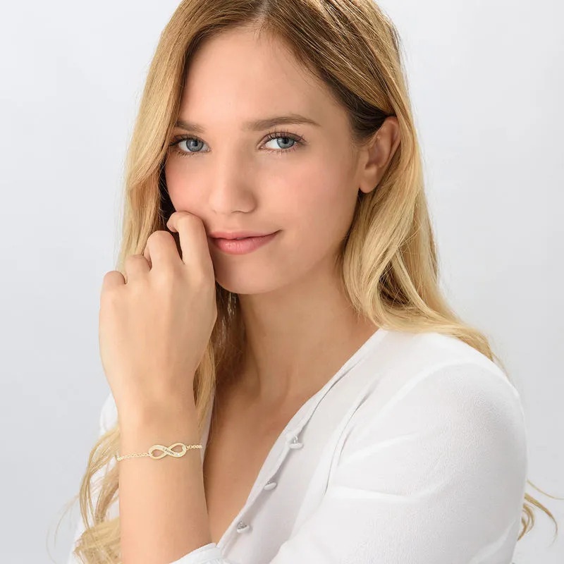 Woman wearing a gold plated infinity ring with an inscription 