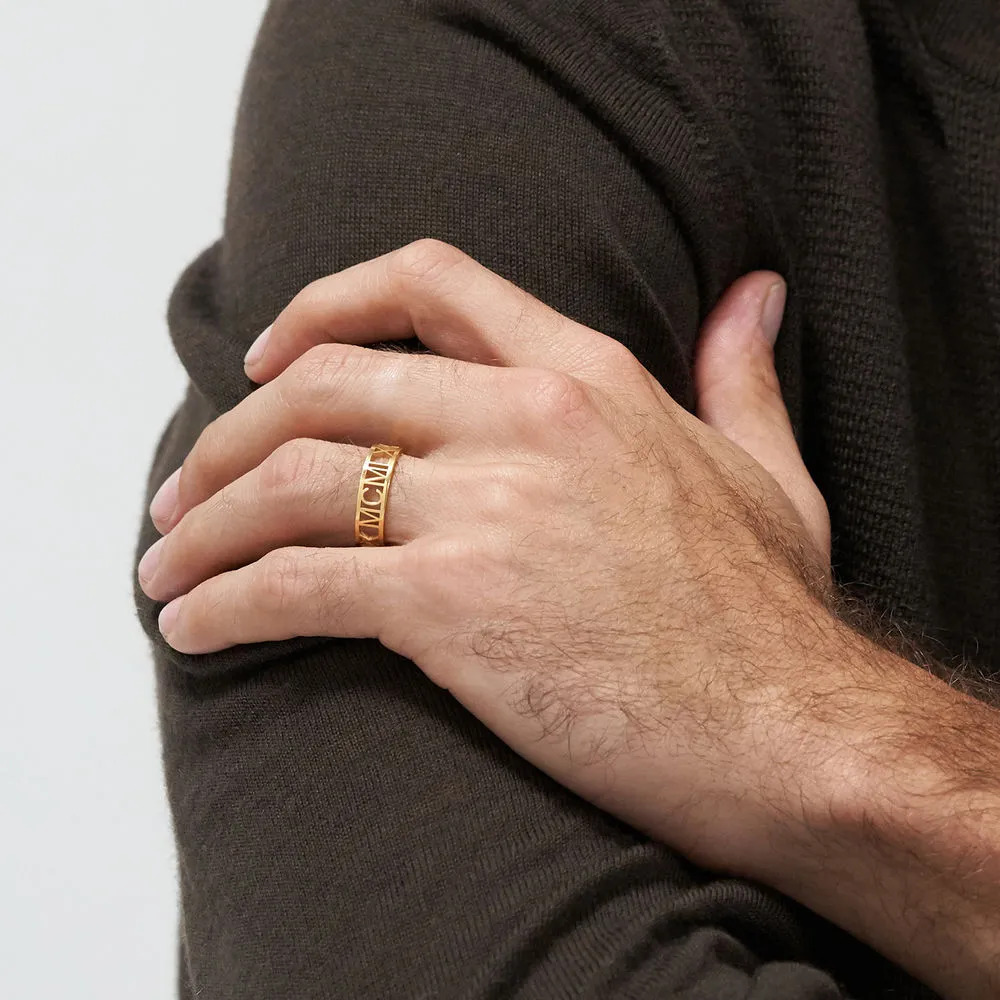 Man wearing a gold plated ring with Roman numeral inscription on his ring finger 