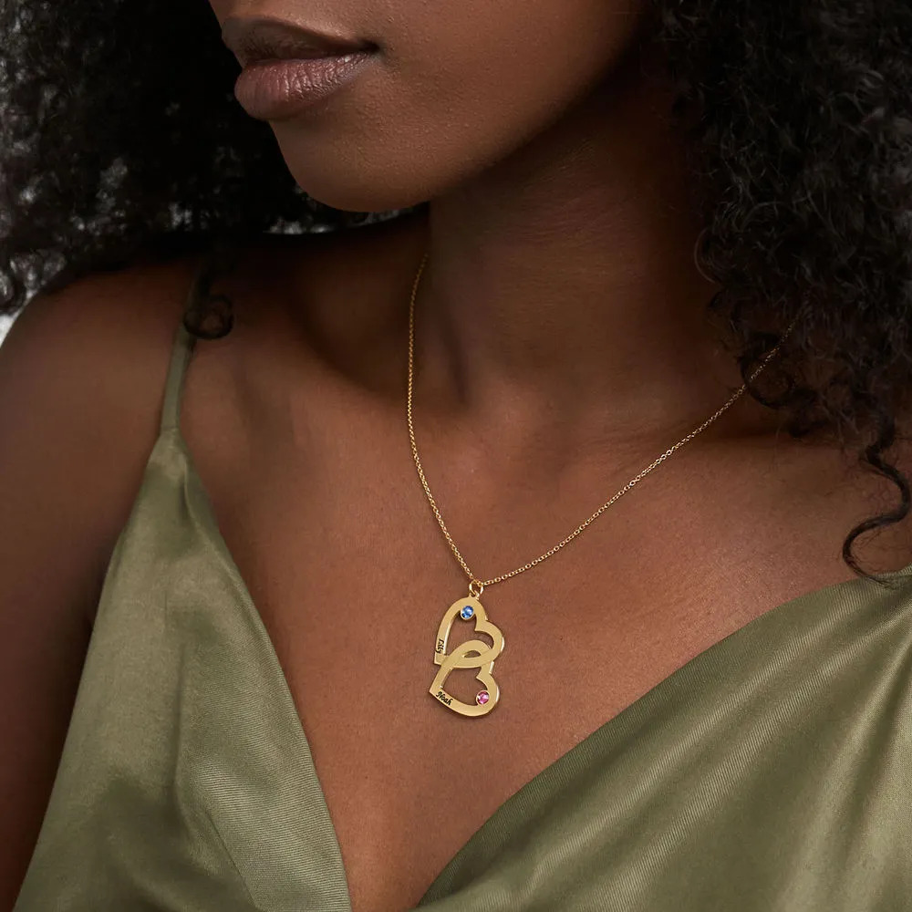 Woman wearing a gold plated necklace with interlocking heart pendants with birthstones