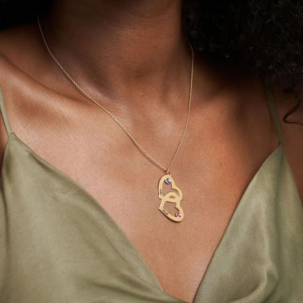Woman wearing a gold plated necklace with interlocking heart pendants with birthstones