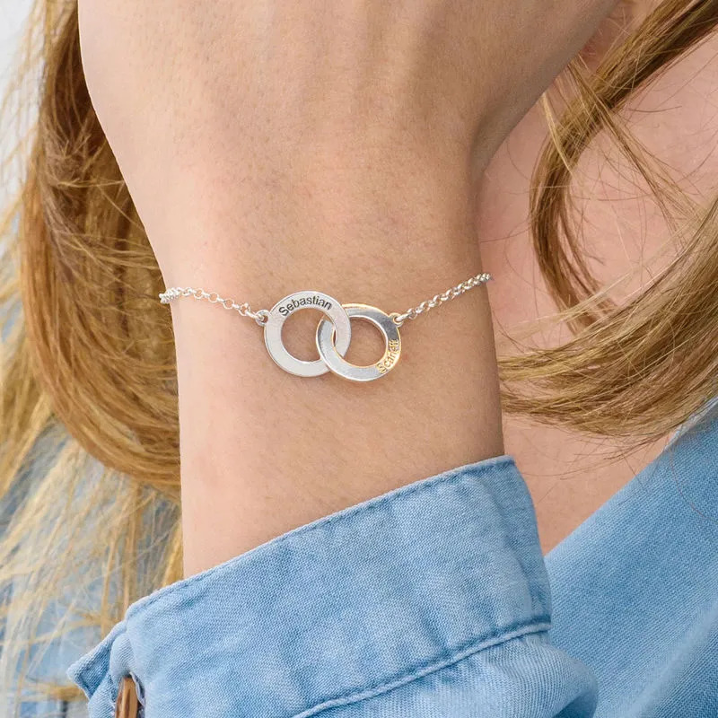 Woman wearing a sterling silver bracelet with an interlocking  heart shaped charms with engravin