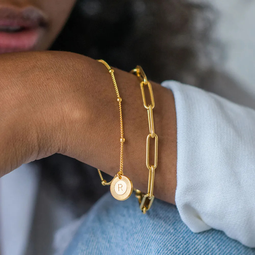 Woma wearing a layered gold bracelet with circular pendants 