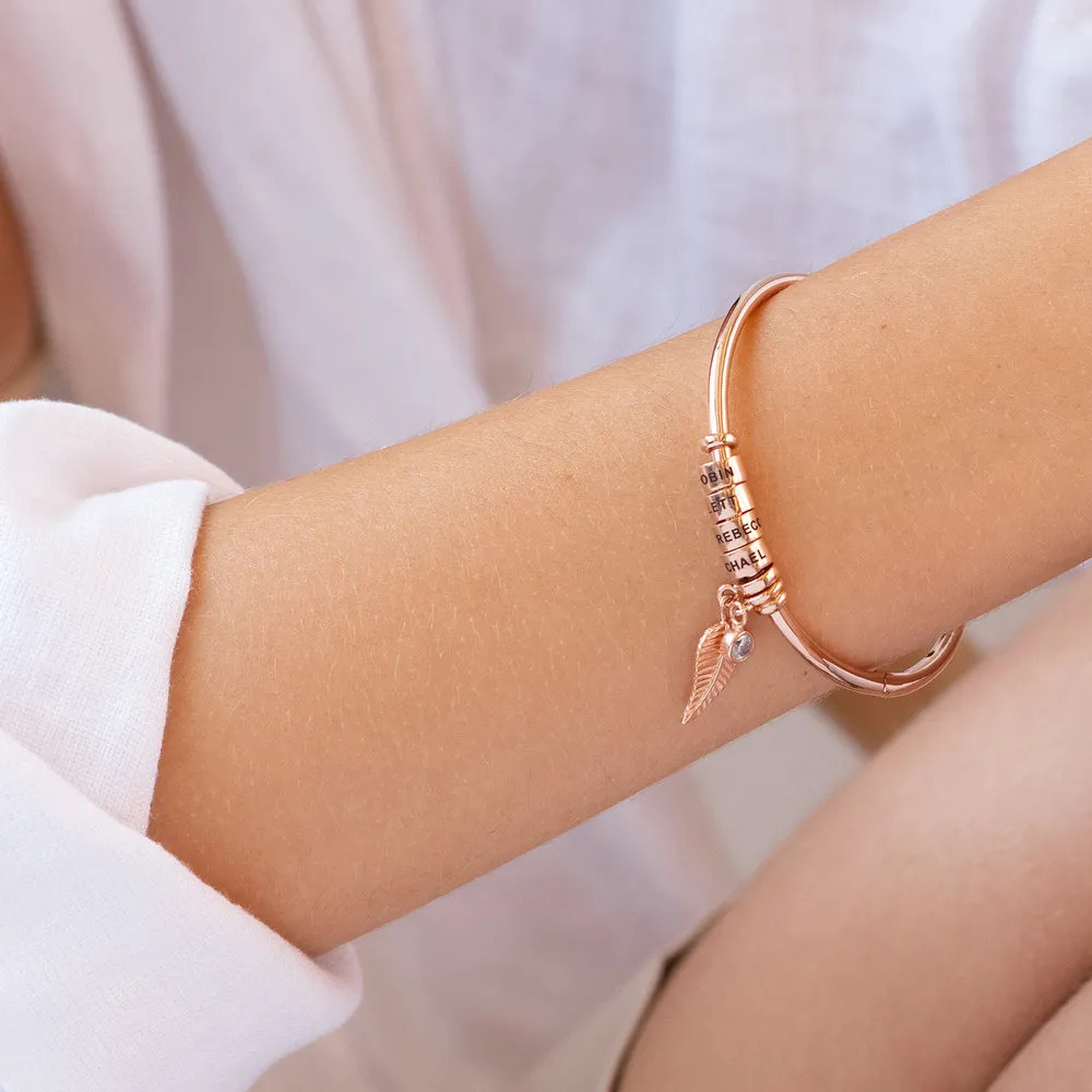 A rose-gold plated bangle bracelet worn on a woman's wrist 