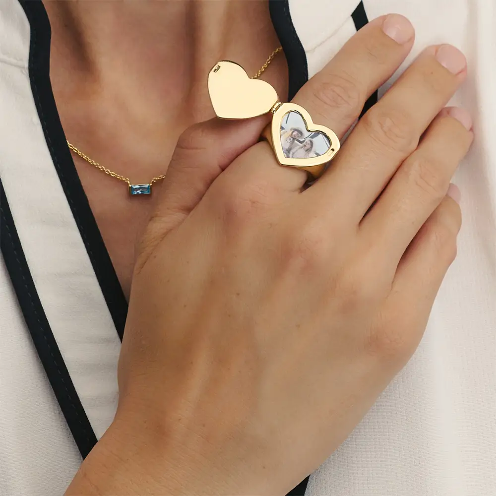 a woman wearing a gold heart shaped photo ring