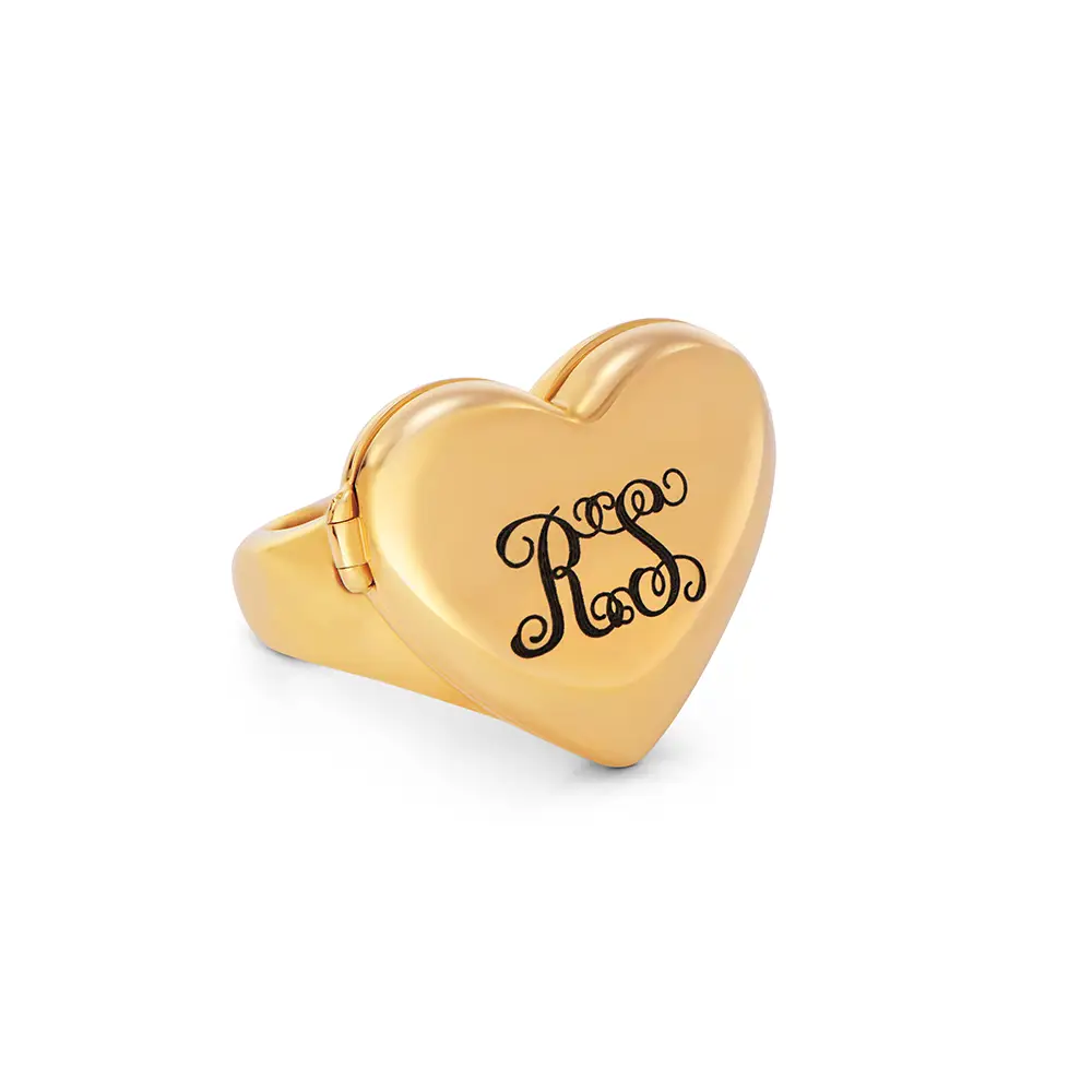 a gold heart shaped ring with monogram