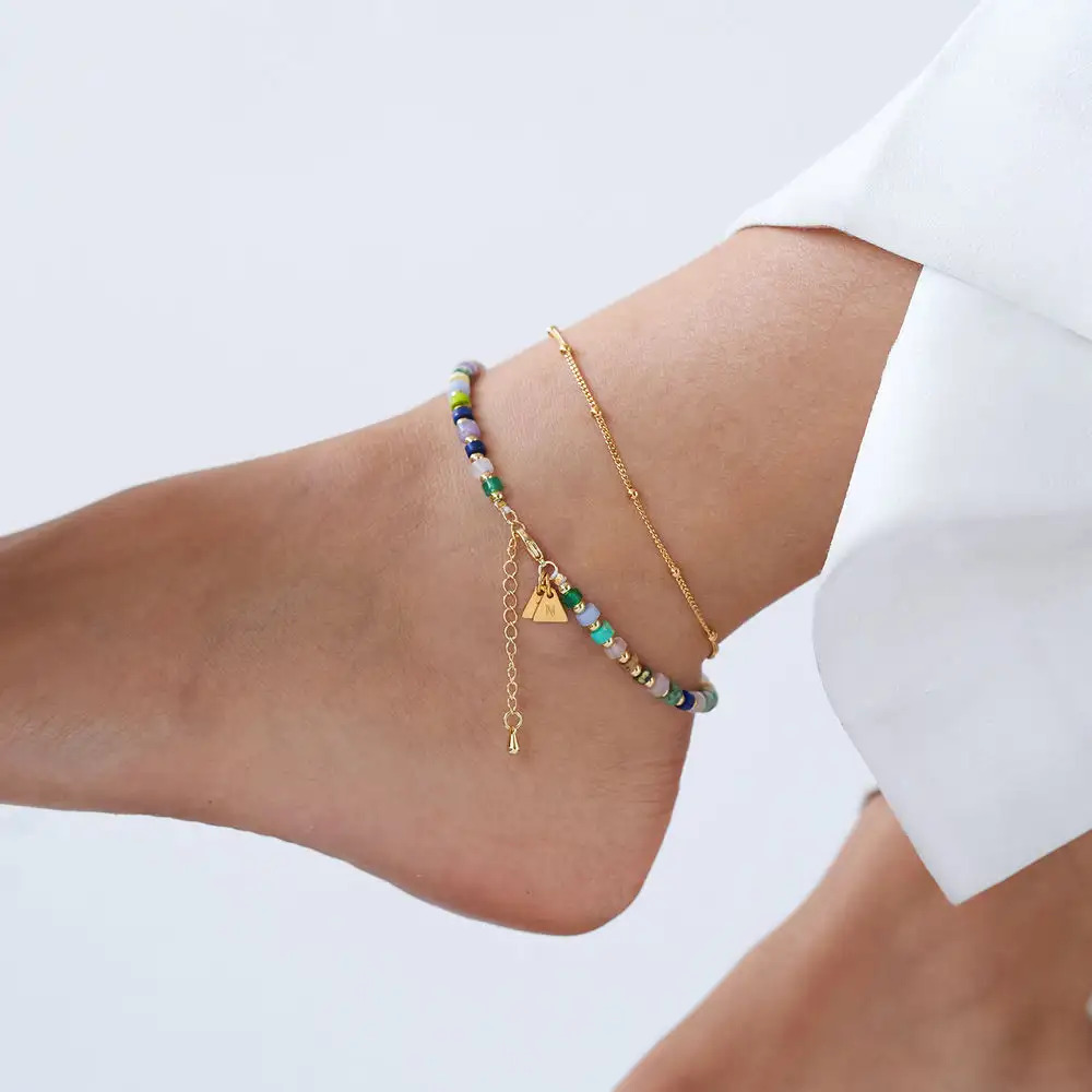 Close-up of a woman's ankle with a colorful beads and gold chain anklet