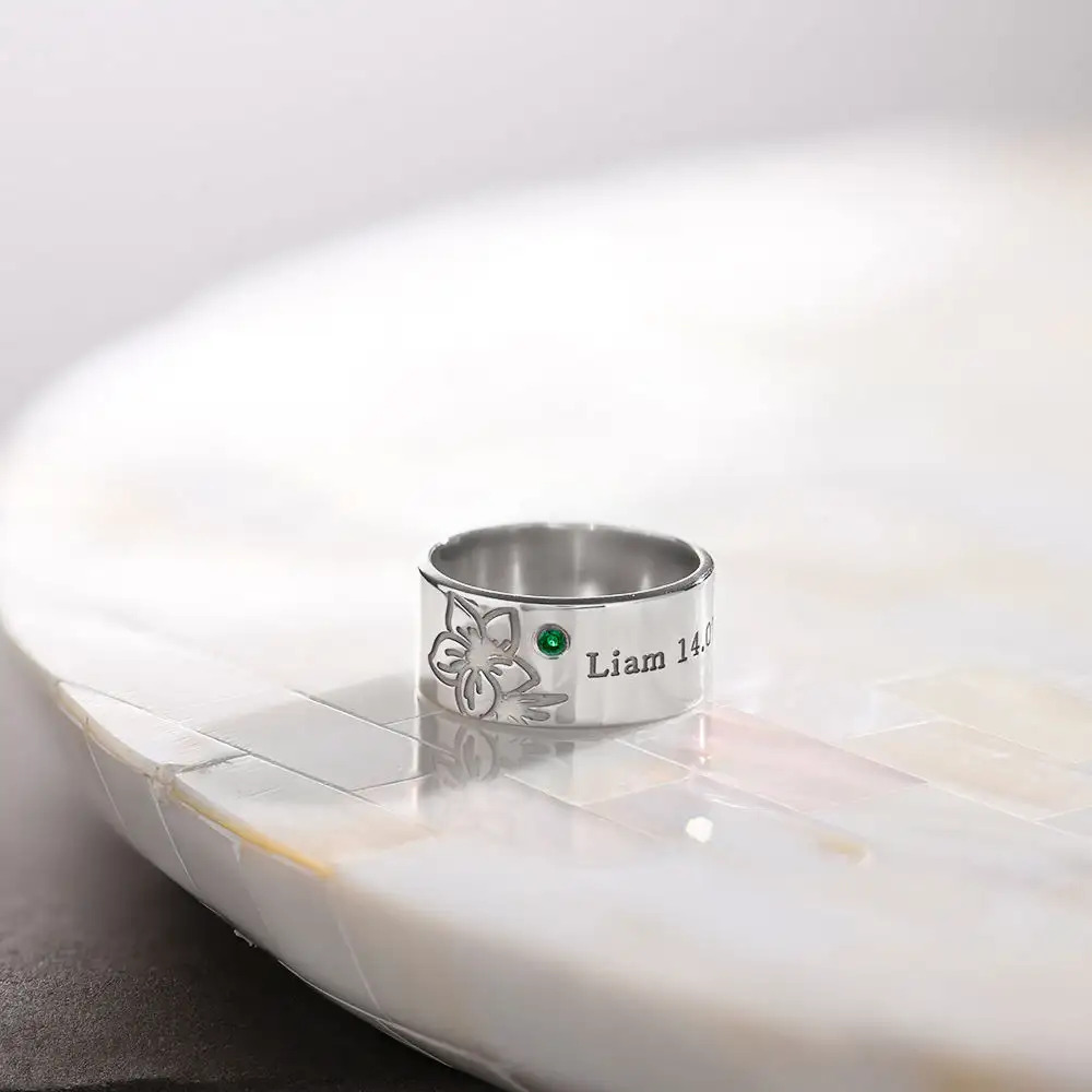 Silver inscribed ring with a birthstone on a white table
