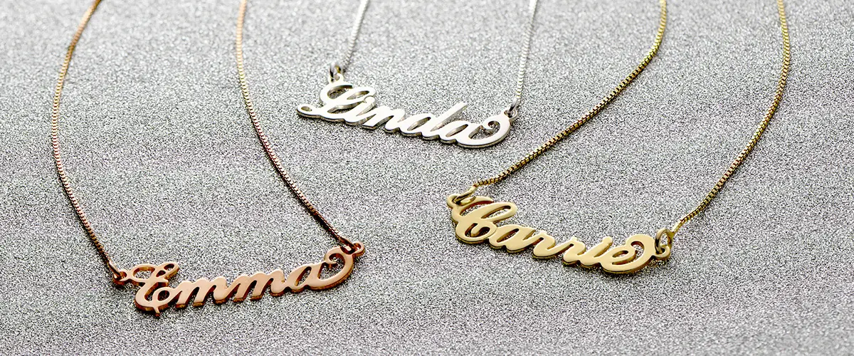 three personalized name necklaces on a table