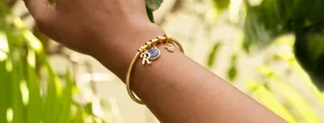 a woman's arm with a gold bracelet and a blue stone