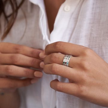 a woman wearing a wedding band and a ring