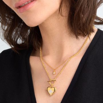 a woman wearing a gold heart shaped locket