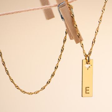a gold necklace with a letter e on it