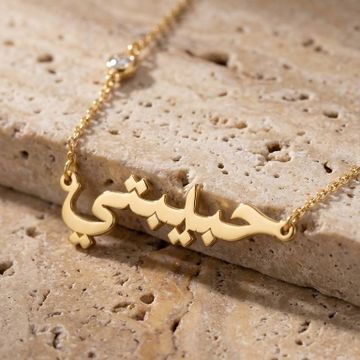 a gold necklace with arabic darling writing on it