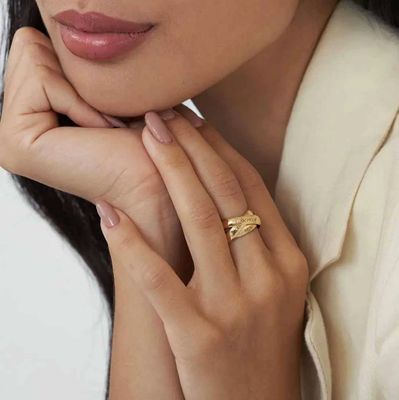 A woman wearing a layered gold engraved ring
