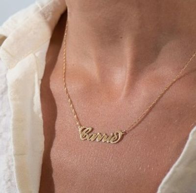 A 14k gold personalized name necklace that reads "Carrie" around a girl's neck