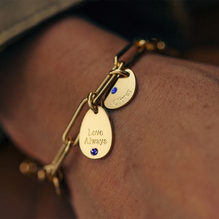 a close up of a person wearing a gold bracelet with blue birthstones