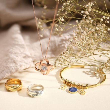 A rose gold neckalce, Gold bracelet and silver and gold rings on a light background