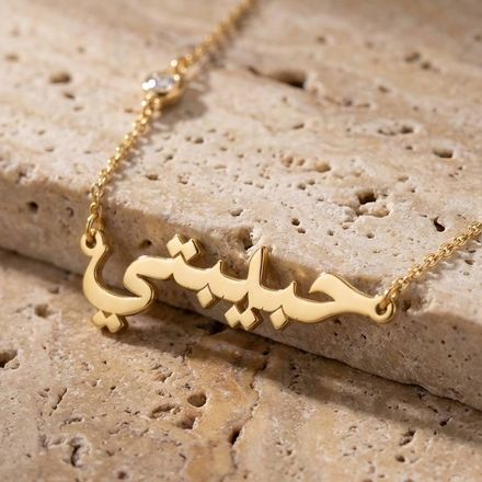 a gold necklace with arabic darling writing on it