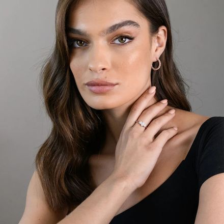 Woman wearing a rose gold plated sterling silver ring with diamond detailing on her middle finger 
