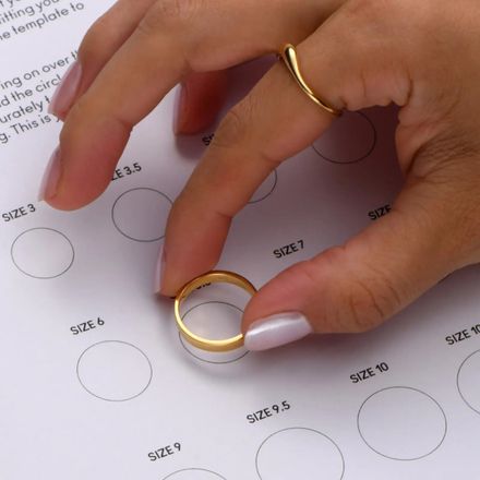 a woman's hand with a ring on top of a sheet of paper