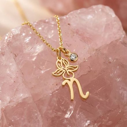 a gold N initial necklace with a flower and a diamond