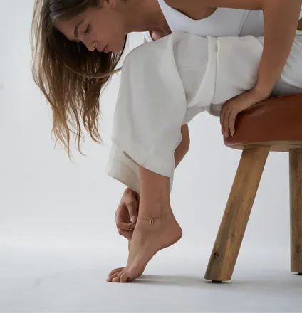 a woman sitting on a chair with her foot on a stool