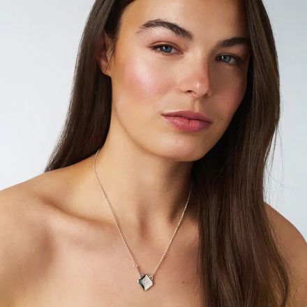 a woman wearing a necklace with a diamond on it