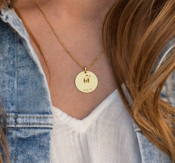 Woman wearing gold necklace with a disc engraved with a family and their initials