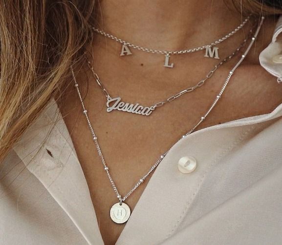 Woman wearing 3 silver Name Necklaces from MYKA of different lengths and designs