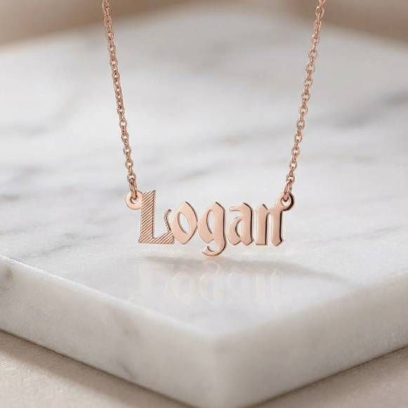 a personalized Logan name necklace on a marble surface