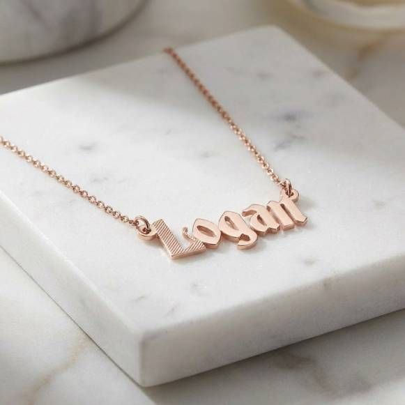 a personalized Logan name necklace on a marble surface