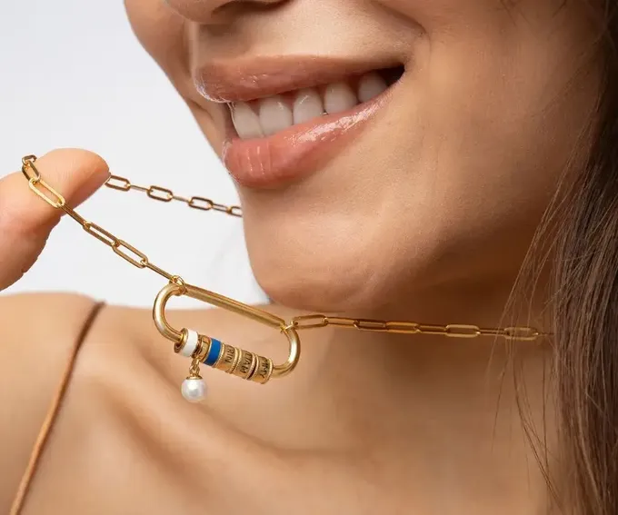 a woman wearing a gold chain necklace and earrings