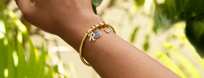 a woman's arm with a gold bracelet and a blue stone