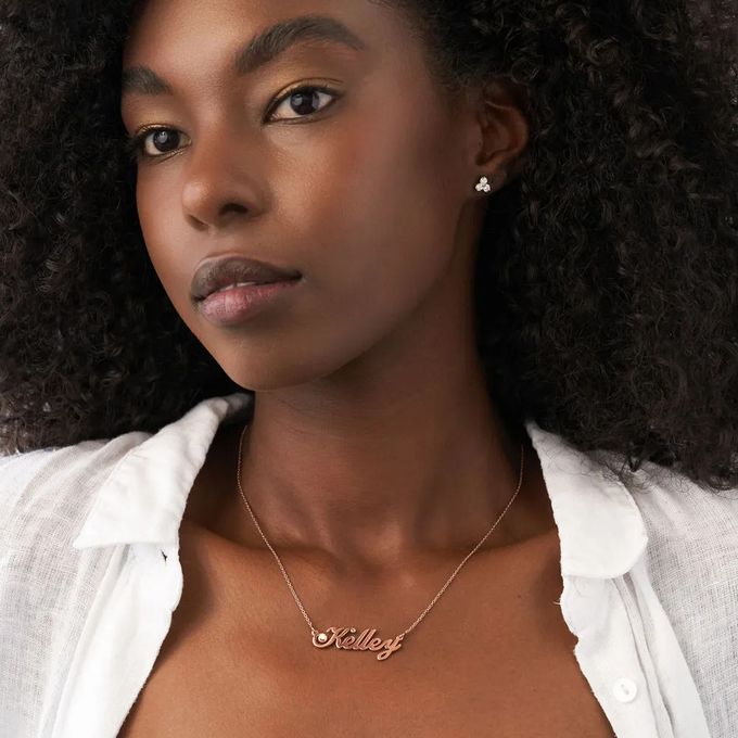 Woman wearing a rose gold necklace with a name pendant and diamond details 