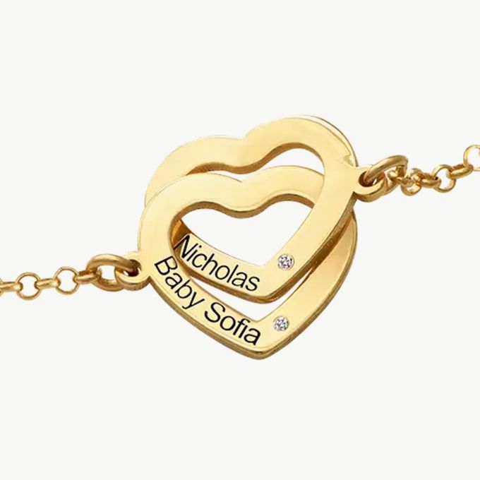 a gold necklace with a heart and two names on it