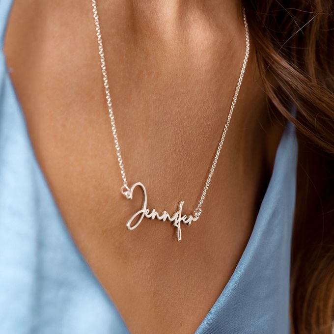 a woman wearing a name necklace with a heart
