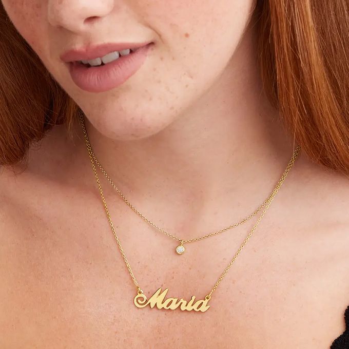 a close up of a woman wearing a name necklace