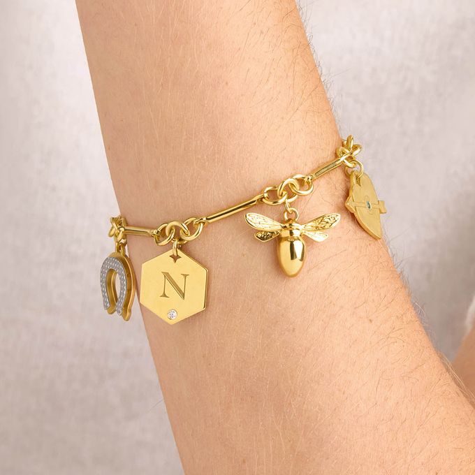 a woman wearing a gold bracelet with charms