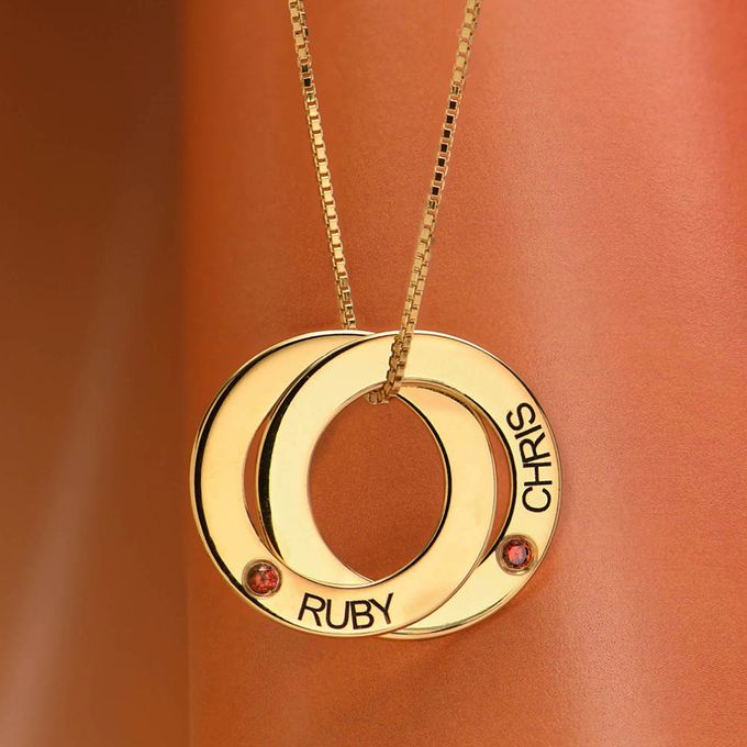 Detail of a gold necklace with name engraving and a ruby