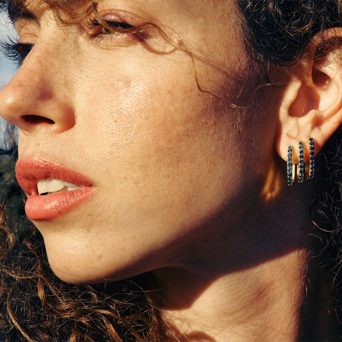 a close up of a person wearing earrings with blue stones