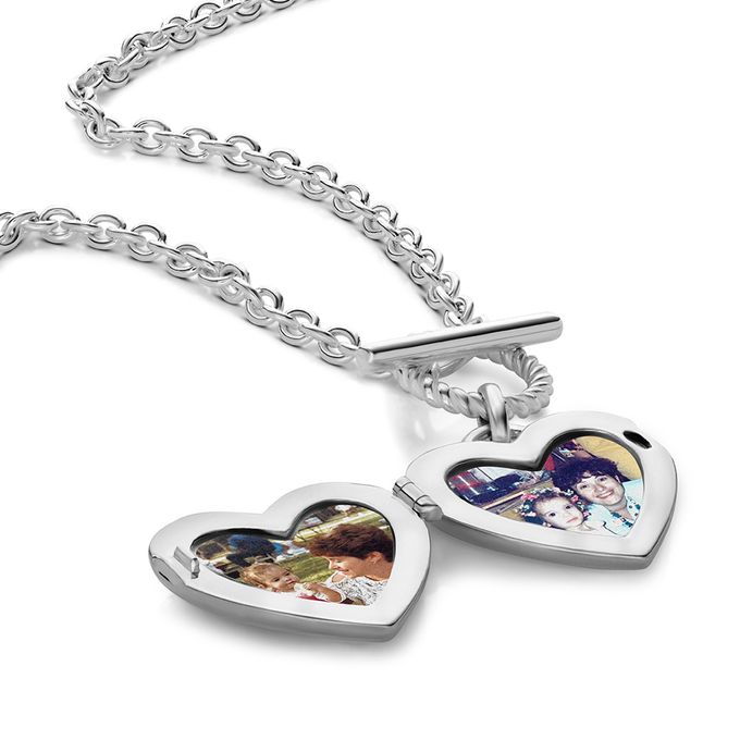 A silver open heart locket with photos inside